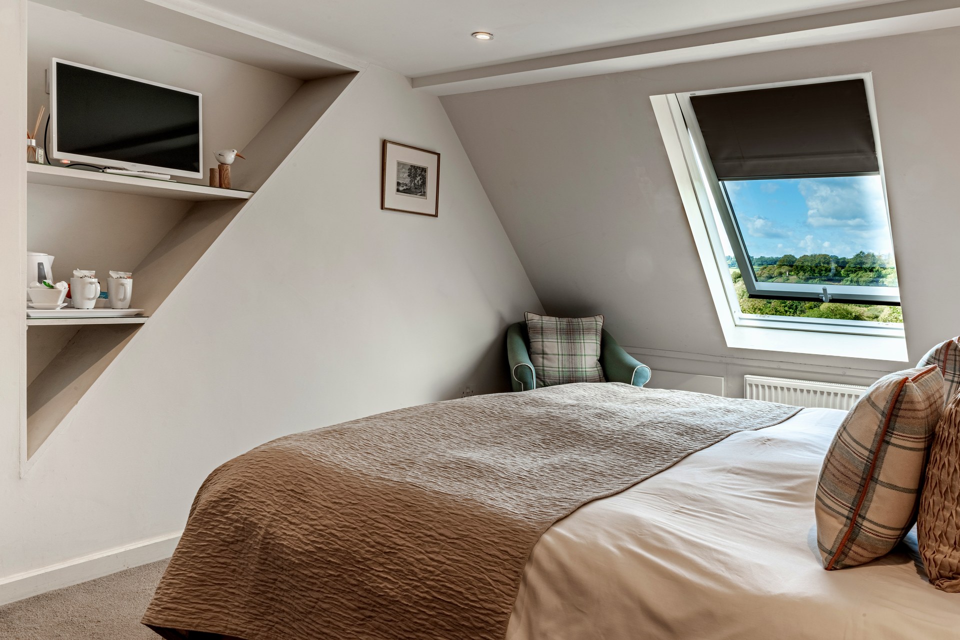 Bed beneath the sloping ceiling and roof window in a Lorne House bedroom